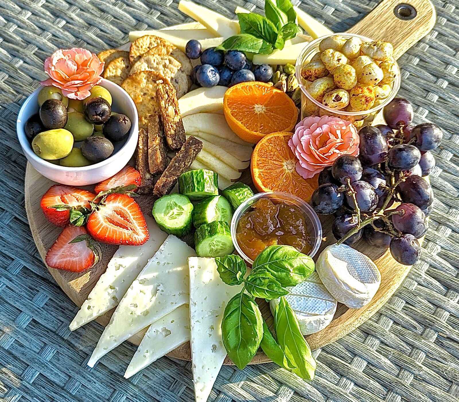 A round charcuterie board with salami roses, grapes and cheese